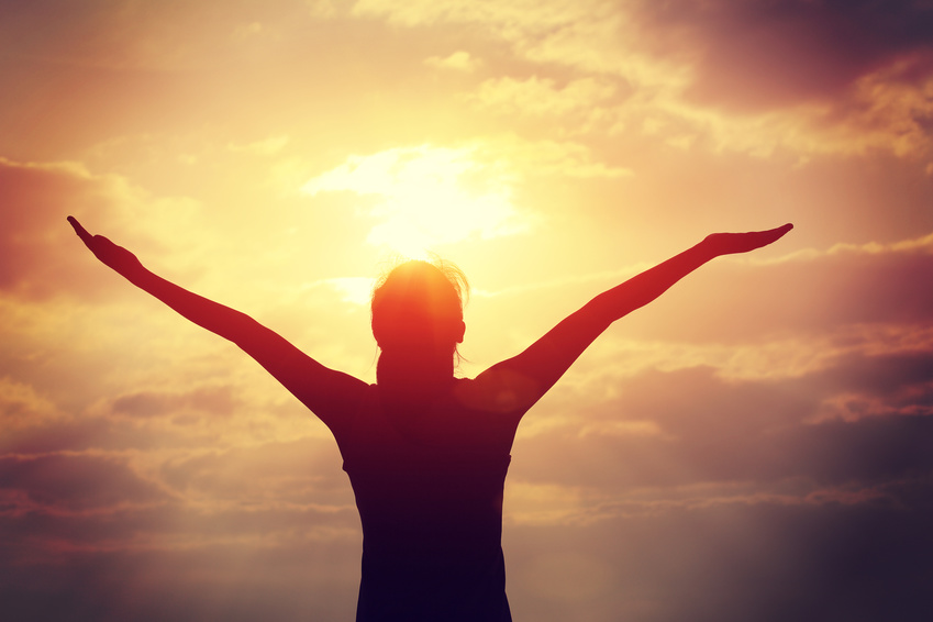 Woman holding hands aloft to greet the dawn