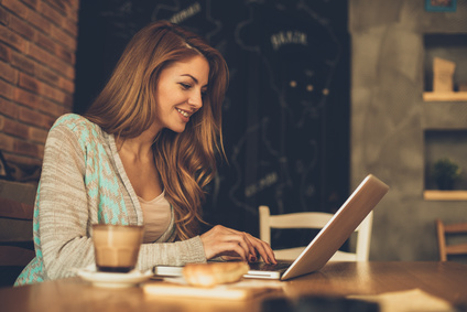 Woman plays the Irish lottery on her laptop in a coffee shop