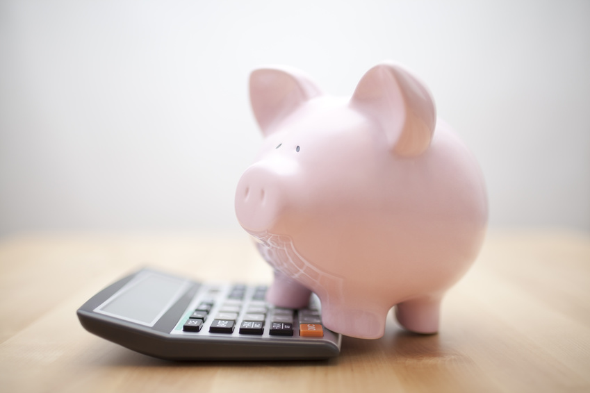 Pink plastic pig stands on a calculator